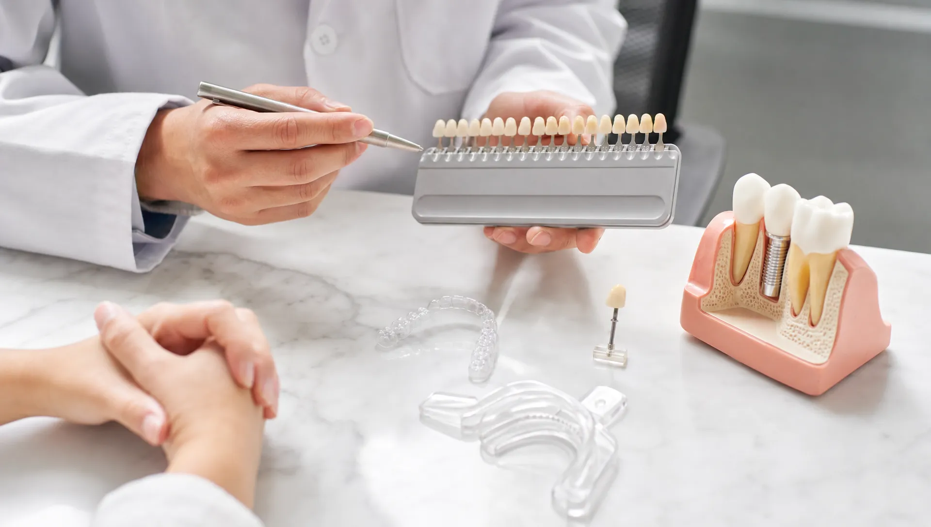 A consultation table shows a shade guide, whitening tray, clear aligner, veneer sample and implant model for comparing cosmetic dental treatment options.