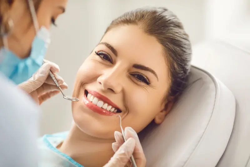 A dentist uses Airflow stain removal on a smiling patient in a clinic