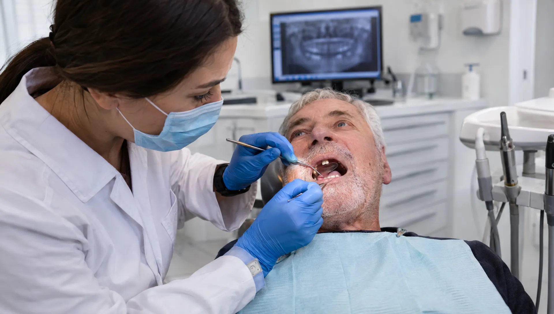 A dentist examines a patient's gums and remaining teeth with a dental mirror during an assessment for multiple missing teeth.