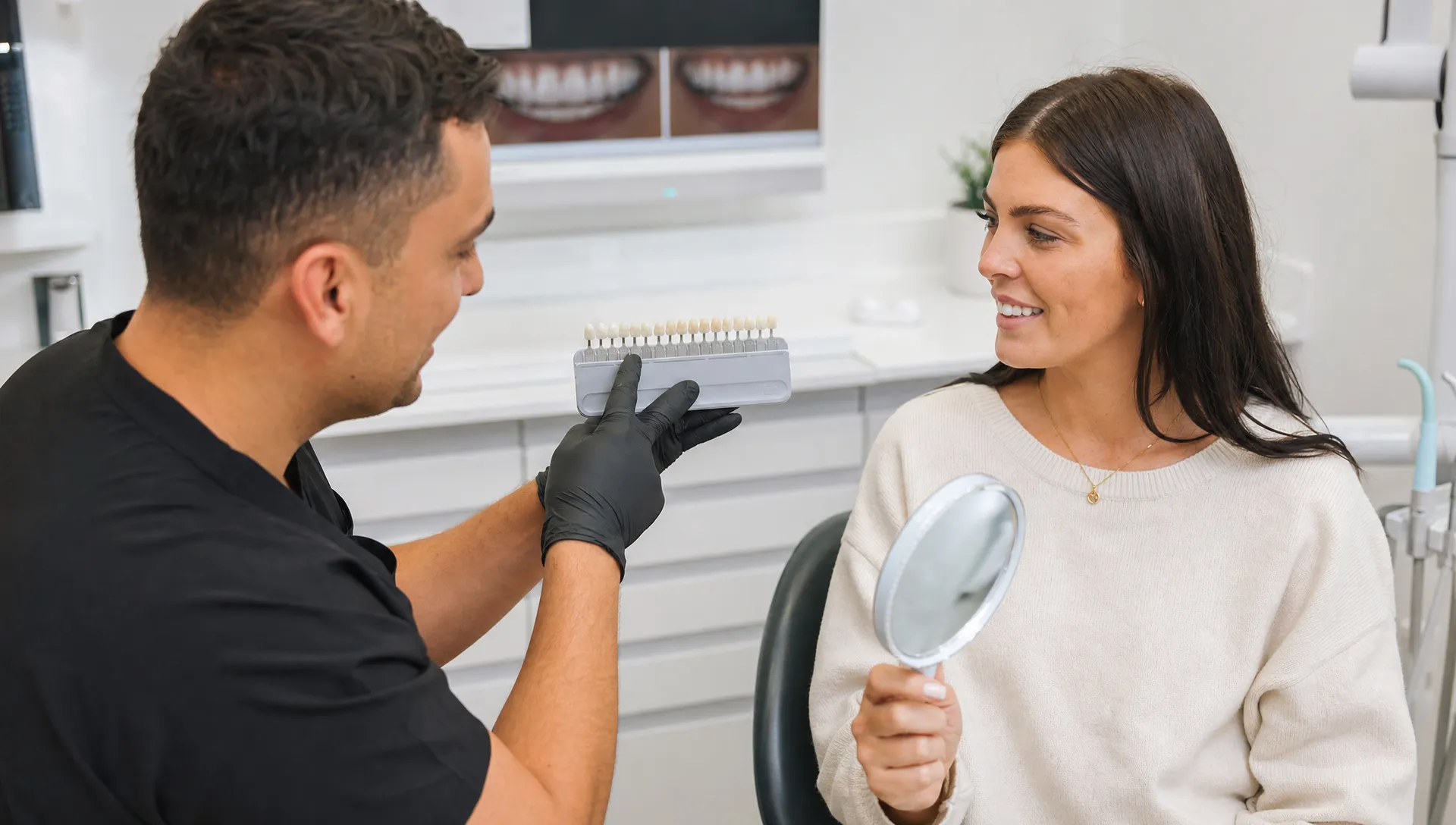 An adult patient and dentist discuss tooth shade and smile shape with a shade guide during a composite bonding consultation.